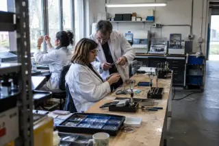 Adultes en reconversion montant des verres sur des montures dans l’atelier d’une école d’optique