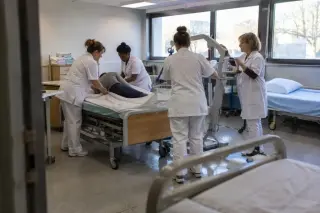 Des stagiaires aides-soignants tournent un patient fictif sur un lit médicalisé, guidés par une formatrice