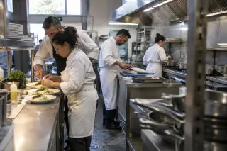 Cuisine pédagogique d’une formation pour adultes : des stagiaires en veste blanche dressent des assiettes près d’un chef
